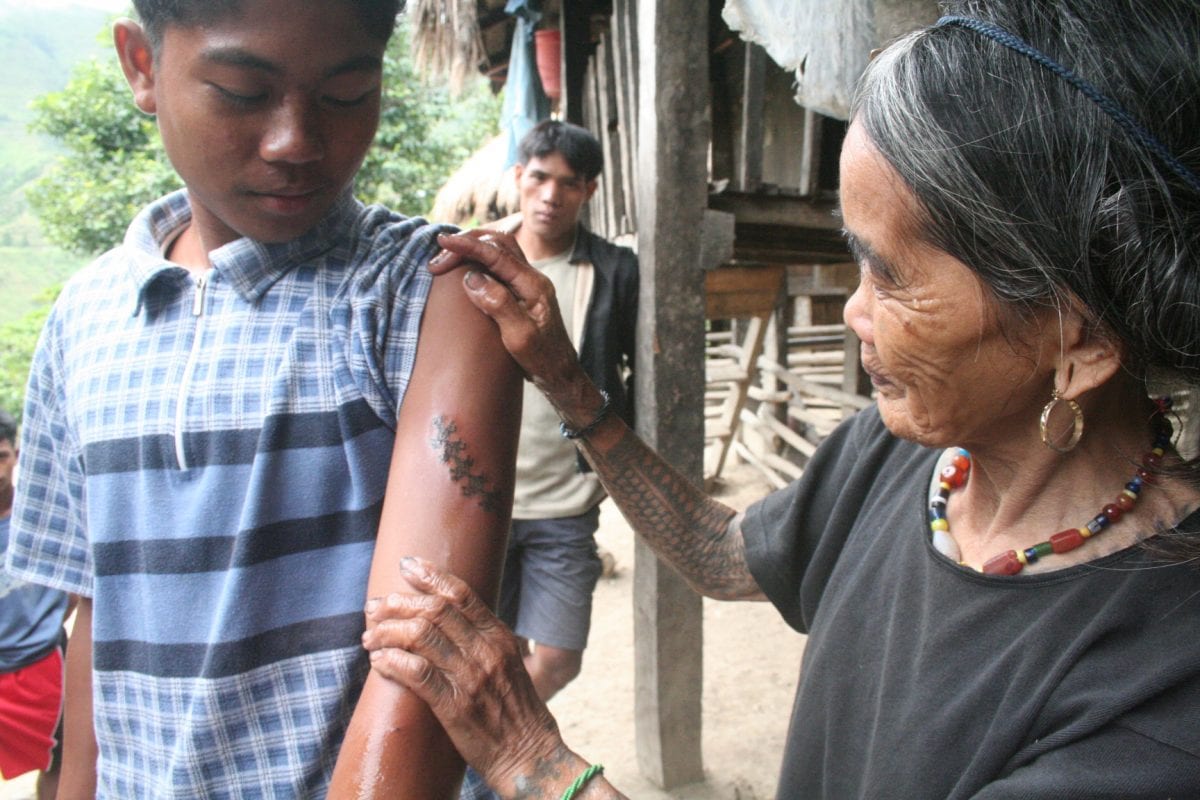 Meet the world's oldest tattooist whose tribal inkings are 20 TIMES more painful than normal body art. See SWNS story SWTATT; Filipino spinster Whang-od, 97, dedicated her life to tattooing villagers since she learned the ancient practice aged just ten. She uses charcoal and water to make the ink, which is then hammered inside the skin using a THORN from a tree. Hundreds of 'tattoo tourists' a year now trek to her remote mountain village in Kalinga province, some ten hours from the Philippines capital Manilla, for one of her ancient designs.