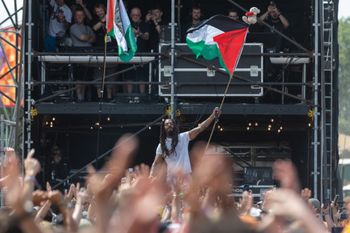 GLASTONBURY, ENGLAND - JUNE 28: Bob Vylan waves a Palestinian flag as he performs on the West Holts stage during day four of Glastonbury Festival 2025 at Worthy Farm, Pilton on June 28, 2025 in Glastonbury, England. Avon and Somerset Police have announced that they have launched a criminal investigation into the performances of Bob Vylan and also of the Irish-language rap band Kneecap who are known for making pro-Palestinian and political comments during their live performances and have attracted controversy in the past. Established by Michael Eavis in 1970, Glastonbury has grown into the UK's largest music festival, drawing over 200,000 fans to enjoy performances across more than 100 stages. In 2026, the festival will take a fallow year, a planned pause to allow the Worthy Farm site time to rest and recover. (Photo by Matt Cardy/Getty Images)