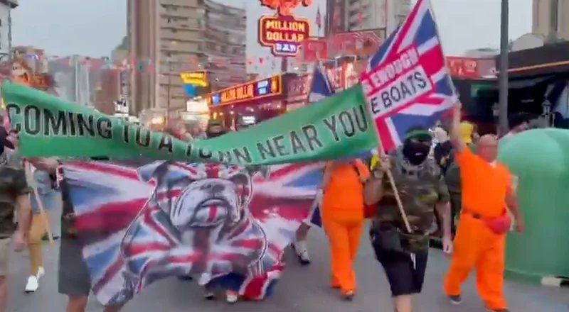 Beyond parody! Brits in Benidorm wave anti-immigration banners during parade