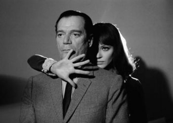 1965, France --- American actor Eddie Constantine and Danish actress and singer Anna Karina on the set of "Alphaville, Une Etrange Aventure de Lemmy Caution" (Alphaville, a Strange Adventure of Lemmy Caution) by her husband French Swiss director, screenwriter and producer Jean-Luc Godard. --- Image by © Georges Pierre/Sygma/Corbis