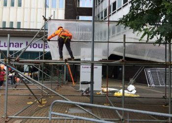 Construction workers were seen erecting 15ft scaffolding in front of a Home Office building, ahead of the latest arrival of "child refugees" from Calais to London. See NATIONAL story NNMIGRANT. Yesterday another 14 migrants arrived in Croydon, with half asking not to be photographed and many covering their faces with towels. Today, around half a dozen construction workers were seen building a structure which appeared to be the foundations of a screen. A construction firm employee confirmed it was a last minute job, organised this morning. The structure reached around the area where all previous coaches from Calais have stopped outside Lunar House, the Home Office building where migrants are interviewed. The labourers were employed by the firm Phoenix Scaffolding. An employee from the firm, who didn't wish to be named, said: "All I know is that it was a last minute job. "We were called up quite early this morning. "I don't know what it is or who called us." The Home Office has been contacted for a commented.