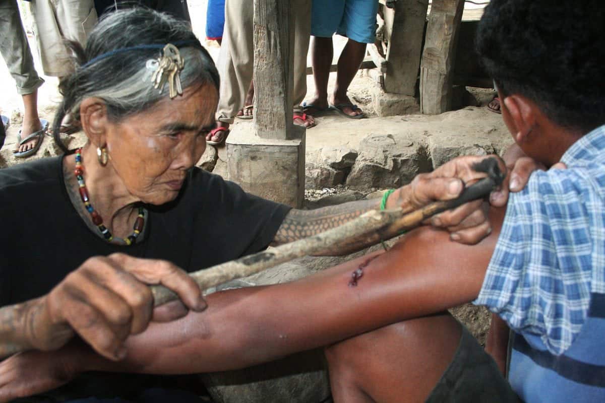 Meet the world's oldest tattooist whose tribal inkings are 20 TIMES more painful than normal body art. See SWNS story SWTATT;  Filipino spinster Whang-od, 97, dedicated her life to tattooing villagers since she learned the ancient practice aged just ten. She uses charcoal and water to make the ink, which is then hammered inside the skin using a THORN from a tree. Hundreds of 'tattoo tourists' a year now trek to her remote mountain village in Kalinga province, some ten hours from the Philippines capital Manilla, for one of her ancient designs.