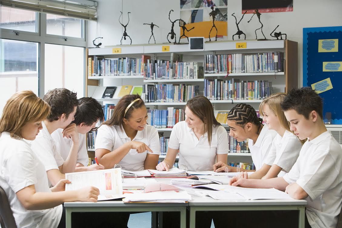 Schoolchildren studying in school library working together on project