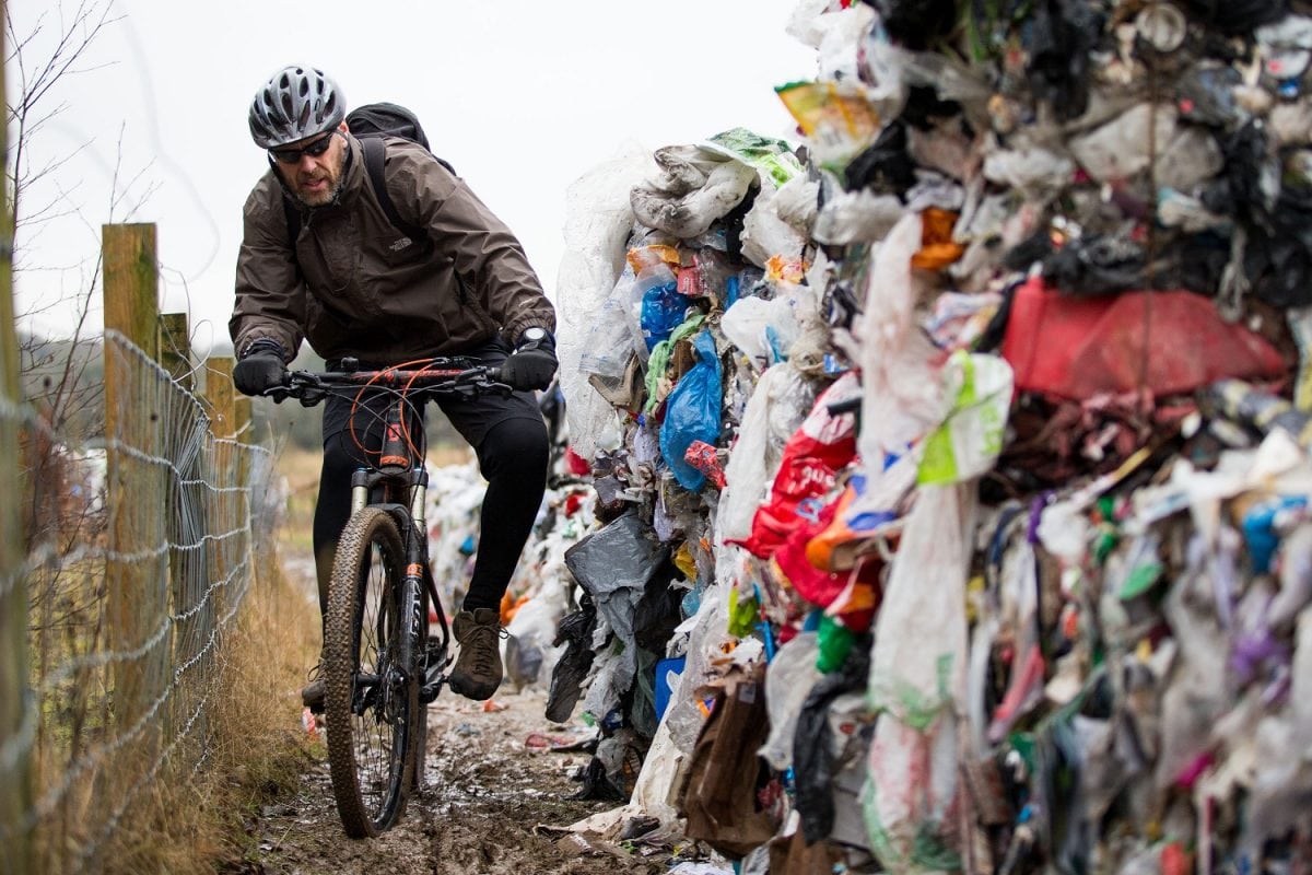 Lee Tanner 49 rides past a mountain of waste such as food products, plastics and paper has been dumped on a cycle path between Biddulph and Brindley Ford, Staffordshire. February 01, 2017.  See NTI story NTIRUBBISH; Police are hunting "industrial fly-tippers" who dumped 50 huge blocks of compressed recyclable rubbish at a beauty spot popular with mountain bikers and walkers. Tens of thousands of discarded plastic bottles, bags and cardboard boxes which had been compacted into 10ft-high cubes were left strewn across the path. Cyclists and walkers were forced to squeeze past the stinking piles of trash after they were discovered on the route between Biddulph and Brindley Ford, Staffs., on Saturday (28/1).  Staffordshire Police and council officials are now investigating in a bid to find out who dumped the rubbish. Dog-walker David Rowe, 66, who discovered the waste, said: "I walked my dog on Friday night and there was nothing there.