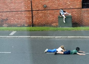 These shocking photographs show children dicing with death as they dodge cars by lying in the middle of a busy ROAD. See ROSS PARRY story RPYCHICKEN.  The three children appear to be playing 'chicken', a game involving waiting as long as possible in the way of cars, before jumping away at the last second.  In one of the images, two of the children are seen lying in the middle of the road, while another image shows one the children running out on to the road as a car speeds past.  The photographs, which were taken in Washington, Tyne and Wear, were sent to police by local councillor Dianne Snowdon after local residents raised concerns.  Officers from Northumbria Police are working to identify the children in the images so their parents can be spoken to about their reckless behaviour but police also want to remind people of the dangers of playing on and near busy roads.
