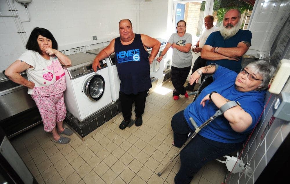 Local residents at Antona Court, Shirehampton, led by Steve Norman (centre). See SWNS story SWWASH; Council legal chiefs are embroiled in a bizarre legal battle after one of its council tenants sued them because they had stopped him washing his clothes after 8pm at night. Residents living in what is a former sheltered housing complex in Shirehampton share a communal laundry, a room which contains two washing machines and two tumble dryers.That room in Antona Court, in the shadow of the M5 approach to the Avonmouth Bridge, was always open whenever residents needed to go there, 24 hours a day.