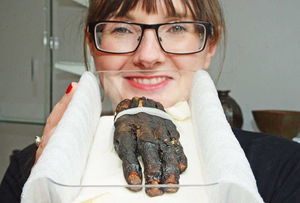 Swindon Museum collections manager Stef Vincent with their severed Egyptian hand. See SWNS story SWHAND; A severed hand wasn’t what Stef Vincent expected to find in a plastic box as she went about her job at Swindon Museum and Art Gallery. The collections project manager was sorting through objects in the cramped stores at the building in Bath Road when she made the gruesome discovery. Peeling away the lid of the box she found a withered ancient Egyptian hand, which museum staff now know belonged to a woman mummified thousands of years ago. It was a chance discovery for Stef, 35, who has worked at the Bath Road museum since 2014.