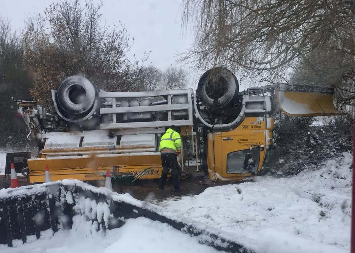 Shocking photos show the moment a gritter overturned on an icy road and landed on its roof
