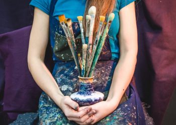 Female artist holding a bunch of brushes. Creativity and imagination concept