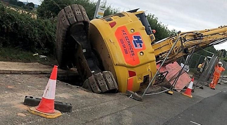 Workmen left red-faced after digger falls into a hole causing traffic chaos