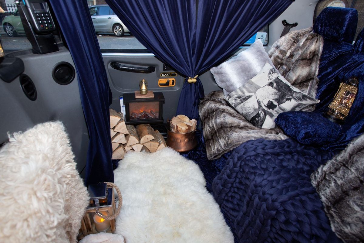 London taxi decked out as a mobile log cabin complete with roaring FIREPLACE