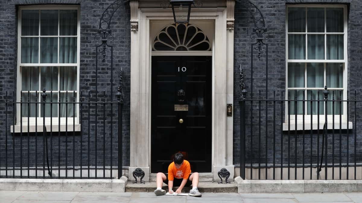 Jess Phillips leaves her son outside No 10 to protest education cuts making school hours shorter (PA)