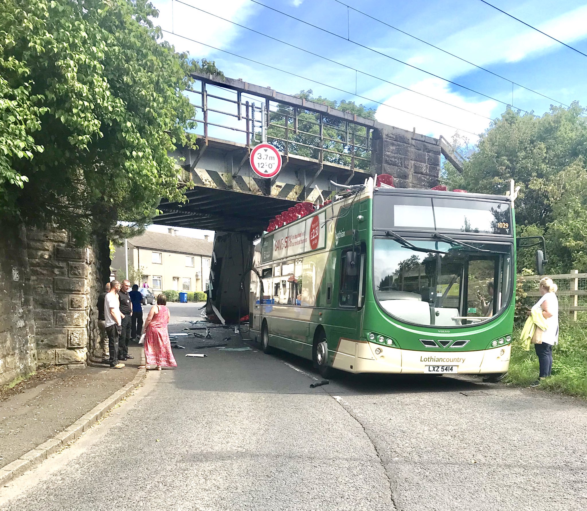 Driver charged after bus roof ripped off in railway bridge crash