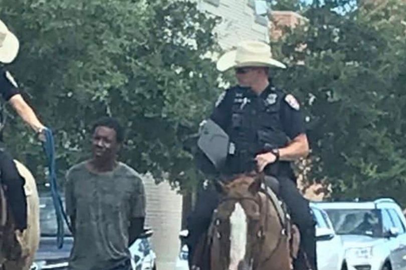 Police on horseback lead black man through street pulling him by rope