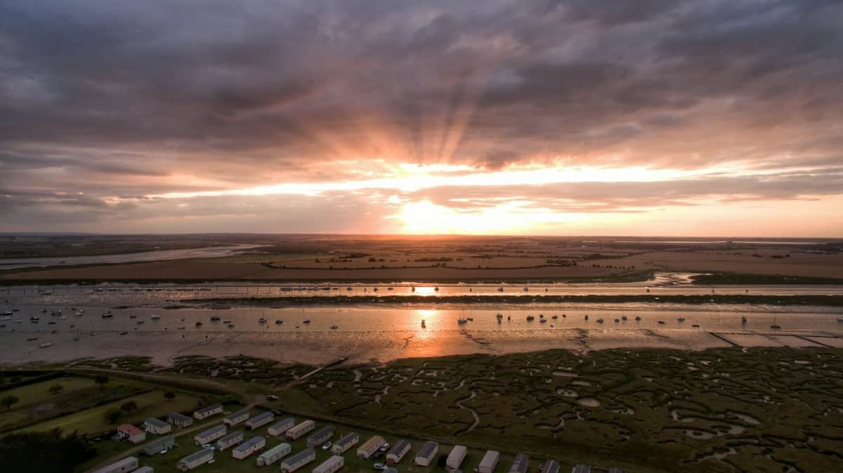 Drone picture shows epic sunset with dramatic rays bursting through a wall of cloud