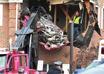 A Porsche is removed form the second story of a building after the convertible went airborne and crashed into the second floor of a New Jersey commercial building early Sunday, killing both of the car's occupants, in Toms River, N.J. (Ed Murray/NJ Advance Media via AP)