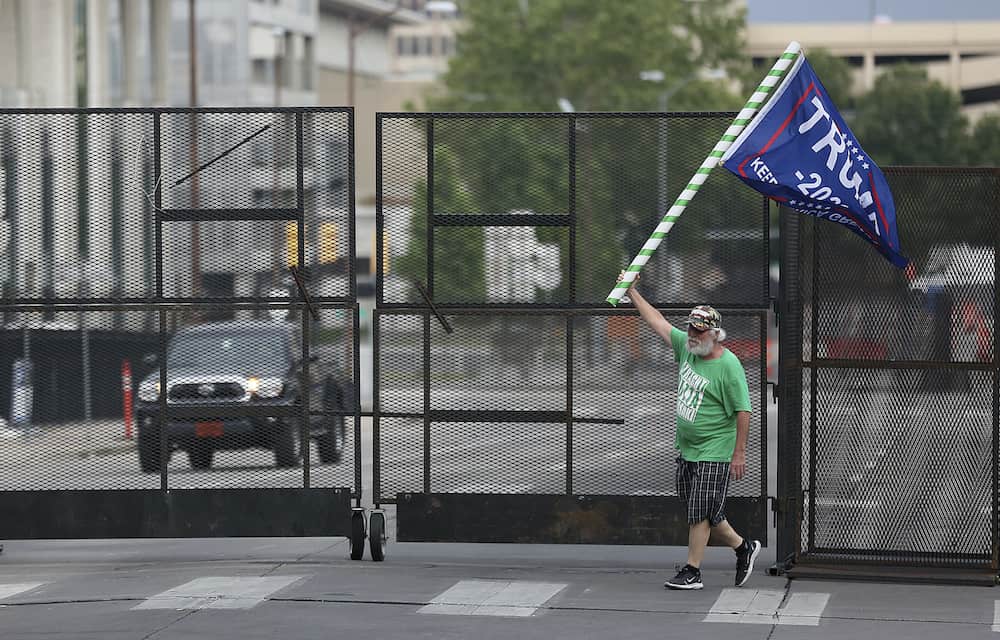 Mike Pellerin waves a Donald Trump campaign flag near a barricade after driving  all night from Austin, Tx. to line up and camp with other Trump supporters on 4th Street and Cheyenne Ave. in downtown Tulsa ahead of Saturday's campaign rally Friday, June 19, 2020. The area for several blocks around the BOK Center is barricaded. Upon arriving Pellerin said he needed to burn some energy before taking a nap. MIKE SIMONS/Tulsa World