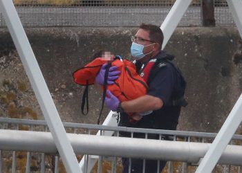 A Border Force officer carries a young child as a group of people thought to be migrants are brought into Dover, Kent, on a Border Force vessel following a number of small boat incidents in the Channel earlier today.