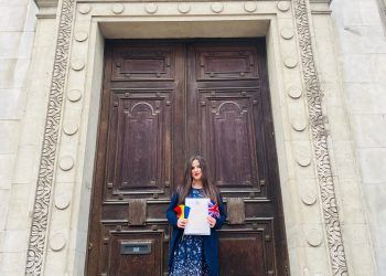 Journalist Andra Maciuca holding her British citizenship certificate and the flags of Romania and the UK.