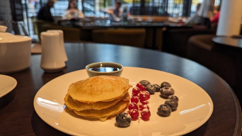 Breakfast of pancakes and berries, lightly dusted with icing sugar